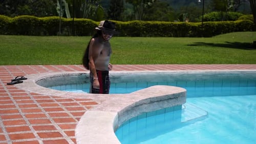 Man and woman enter a beautiful pool on a hot and sunny day in summer