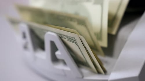 Máquina contadora de dinero. El mostrador de billetes cuenta billetes de cien dólares. Primer plano