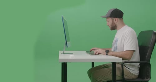 Young Man Developer Using Computer To Write Code on his desktop computer In Green Screen Studio