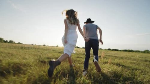 Cheerful Beloved Couple Running and Hugging on Grassy Field in Countryside