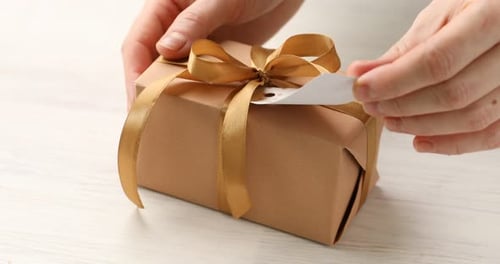 Adding Gift Tag To Present With Golden Ribbon