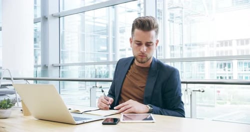 4k video footage of a handsome young businessman working on his laptop in the office