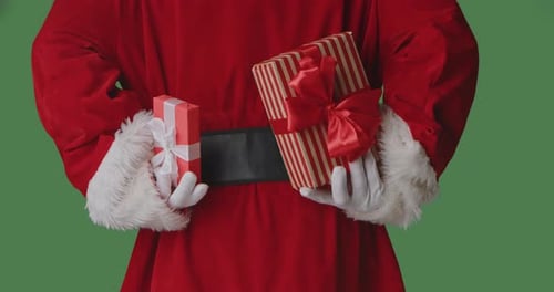 Santa Claus is Holding Gift Boxes with Red Bows on a Green Background Behind His Back