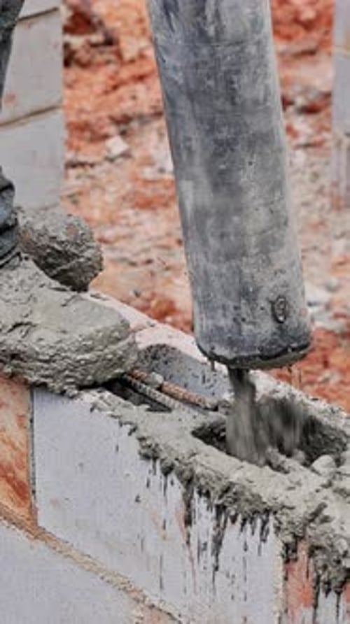 Worker Using Concrete Vibrator on Construction Site to Ensure Proper Settling of Concrete