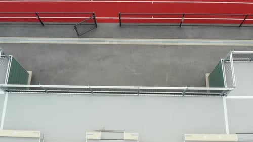 Aerial tilt up of bleachers, track and football, soccer field. No people or spectators at sporting e