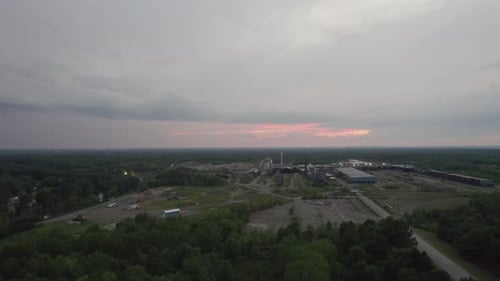 Aerial drone forward moving shot over a large woodworking factory on a cloudy evening. A flight