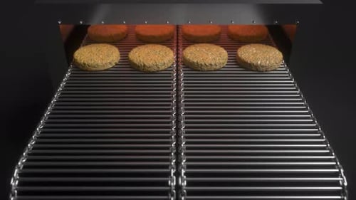 Veggie burgers running on a conveyor belt grill machine, automatic broiler