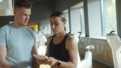 Man and Woman Discuss Fitness Plan at Gym
