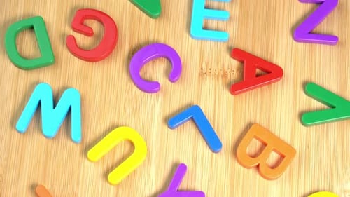 Multicolored letters rotate on a wooden background. The concept of learning, school or college