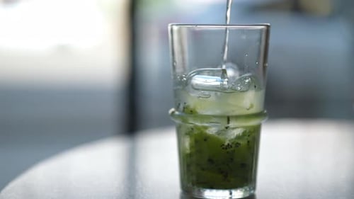 Pouring Soda into Kiwi Drink with Ice