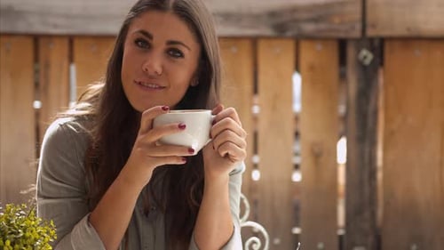 Smiling woman enjoys coffee at outdoor café