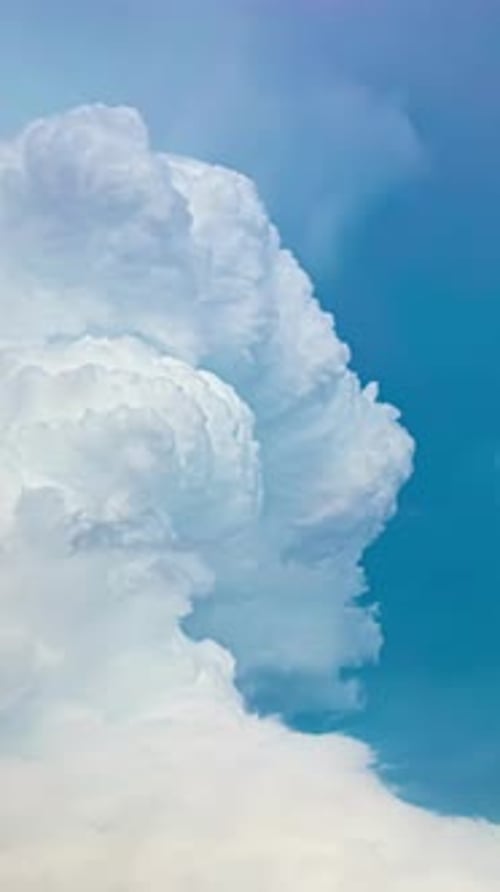 Timelapse of white cumulus clouds forming against blue sky background in vertical shot