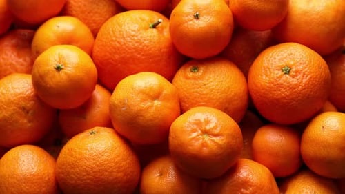 Many fresh ripe tangerines as background, rotating
