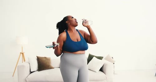 Woman in activewear using phone and drinking water