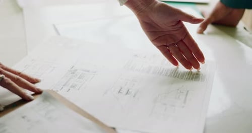 Hands Reviewing Architectural Plans on Table