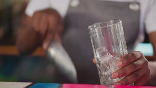 Barman Pours Ice Cubes Into Glass in Bar