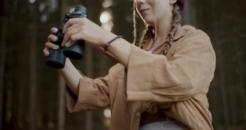 Female Tourist Looking Through Binoculars in Forest