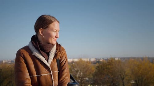 Woman Drinks Coffee in City Park on Autumn Day