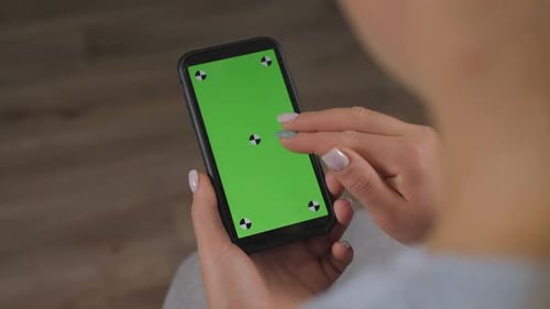 Closeup of Woman's Hand Browsing Smartphone with Green Screen at Home