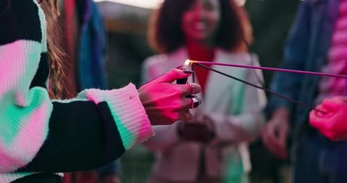 Faíscas, isqueiros ou mãos de pessoas comemorando com chamas, festas ou palitos à noite no novo