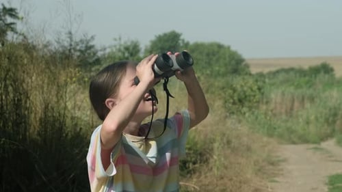 Excited Girl Using Binoculars in a Rural Field