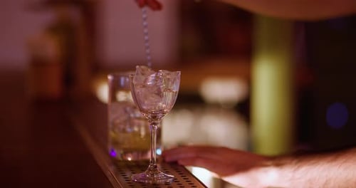 Bartender Mixing Cocktail with Ice and Spoon