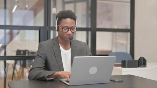 Young Adult Typing at Computer with Headset On