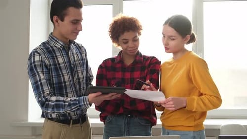 Collaborating Young Adults Discuss Project in Bright Office