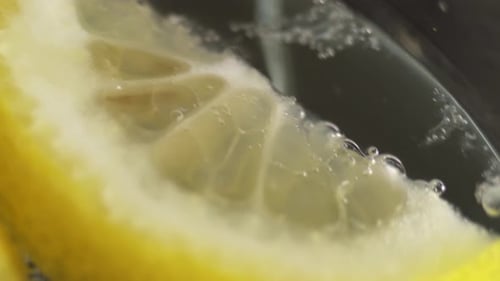 Sparkling water lemon close-up. Glass with refreshing drink is spinning. Glass of water with lemon