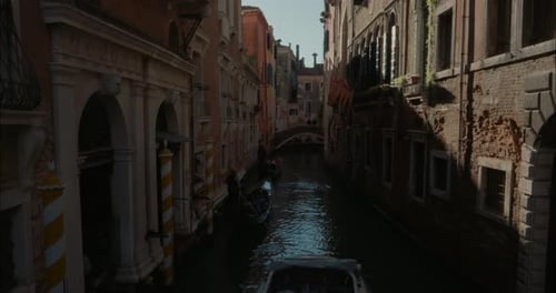A Couple Of Gondoliers Rowing A Narrow Boat Traveling Up And Down The Canals Of Venice