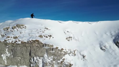 Solo hiker walking on the mountain ridge. Vast winter mountain landscape full of snow.