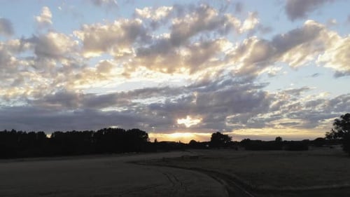Herrlicher Sonnenuntergang und bewölkte Himmelslandschaft über der grünen Wiese und den Maisfeldern auf dem Land.