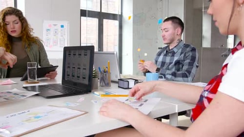 Equipe criativa diversificada colaborando no design da interface do usuário em um escritório moderno