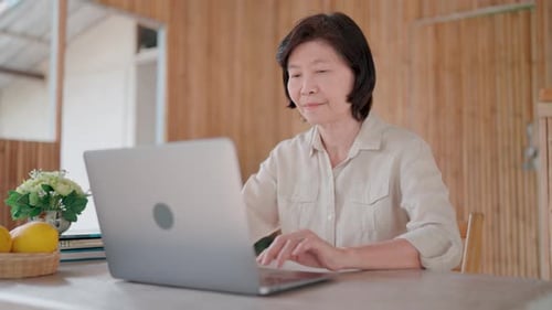 Mature Woman Uses Laptop at Home Indoors