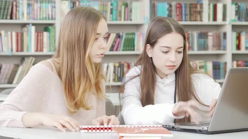 Teen Girls Collaborating on a Project in a Cozy Library