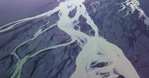 Braided glacial river flowing through volcanic terrain in Iceland. Top down flyover.