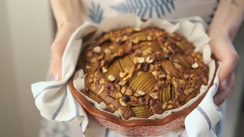 close-up female hands holding hot freshly baked muffin with pear and nuts