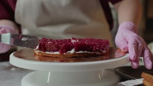 Baker étale la garniture aux framboises sur le gâteau