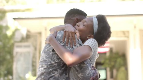 Woman Embracing Soldier in front of Suburban Home