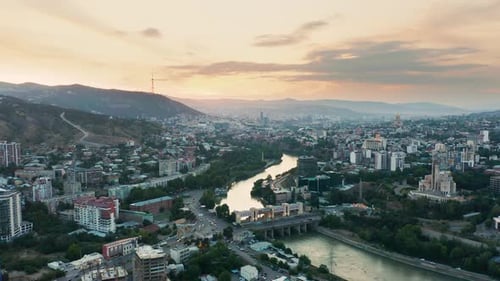 Aerial view of downtown Tbilisi, Georgia at sunset with mountains in the background. Establishing sh