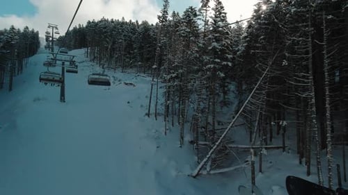 Riding on Ski Lift Between Snow Covered Pinetrees in the Morning POV Shot Winter Vacation Concept