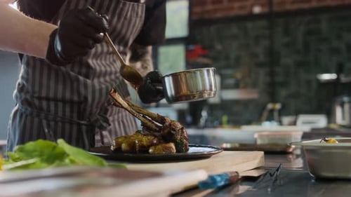 Closeup Chef Adding Sauce To Lamb Rack Dish in Restaurant