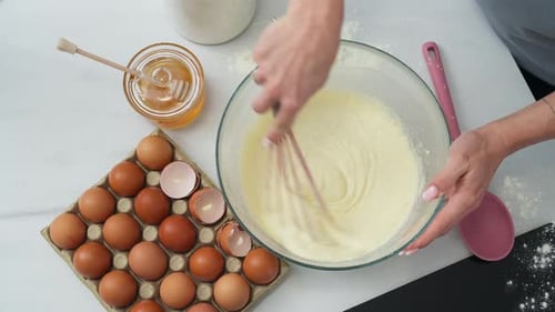 Person, die einen Gebäckteig in einer Schüssel umrührt. Zenital-Schuss