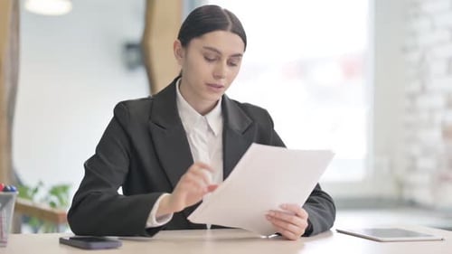 Focused Woman Reviews Documents in a Bright Office