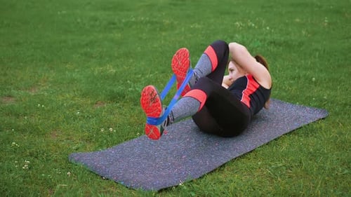 Athletic Woman Crunches with Resistance Band Outdoors
