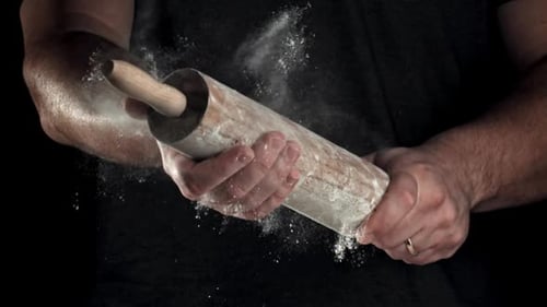 Man Holding Floury Rolling Pin on Black Background