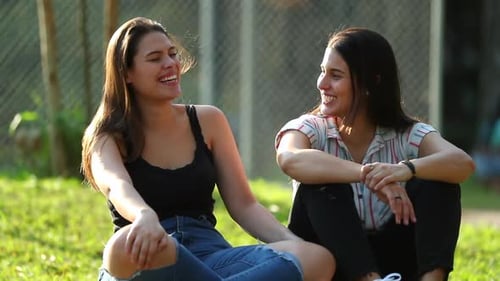 Two friends in conversation outdoors. Friends real life laugh and smile