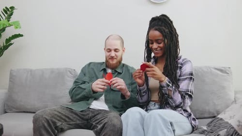 Couple Making Paper Hearts Together on Couch