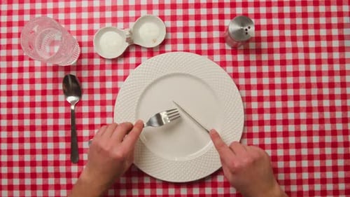 Overhead view of hands with cutlery at table