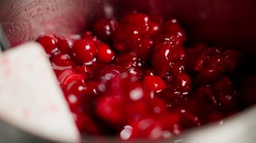 Gros plan dans une cuisine professionnelle : mélanger des cerises avec une spatule dans une casserole pour confiture